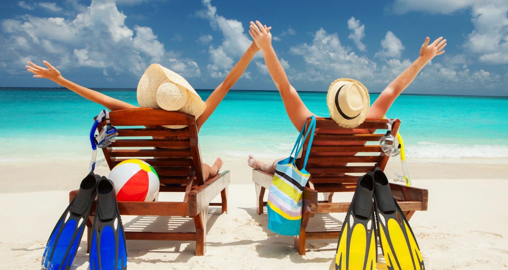 Two women sitting on a beach chair with their arms raised.