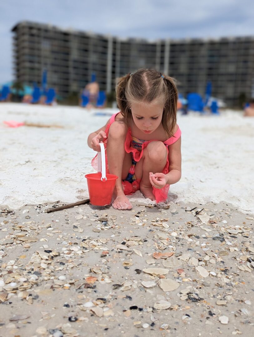 A little girl is playing with sand on the beach